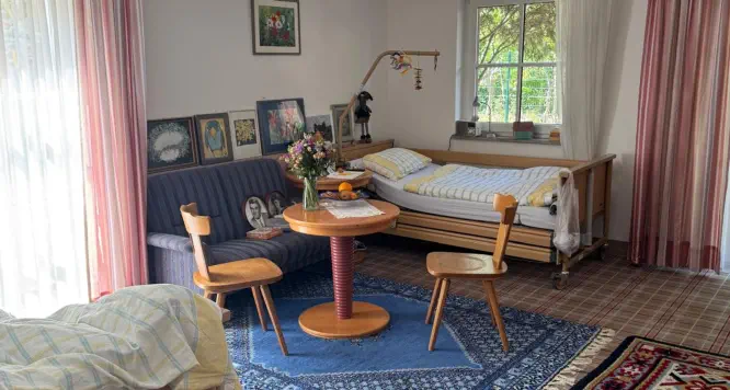 Helles, individuell eingerichtetes Bewohnerzimmer mit Pflegebett, eigenen Möbeln, gerahmten Bildern und frischen Blumen © Foto: Hambückers