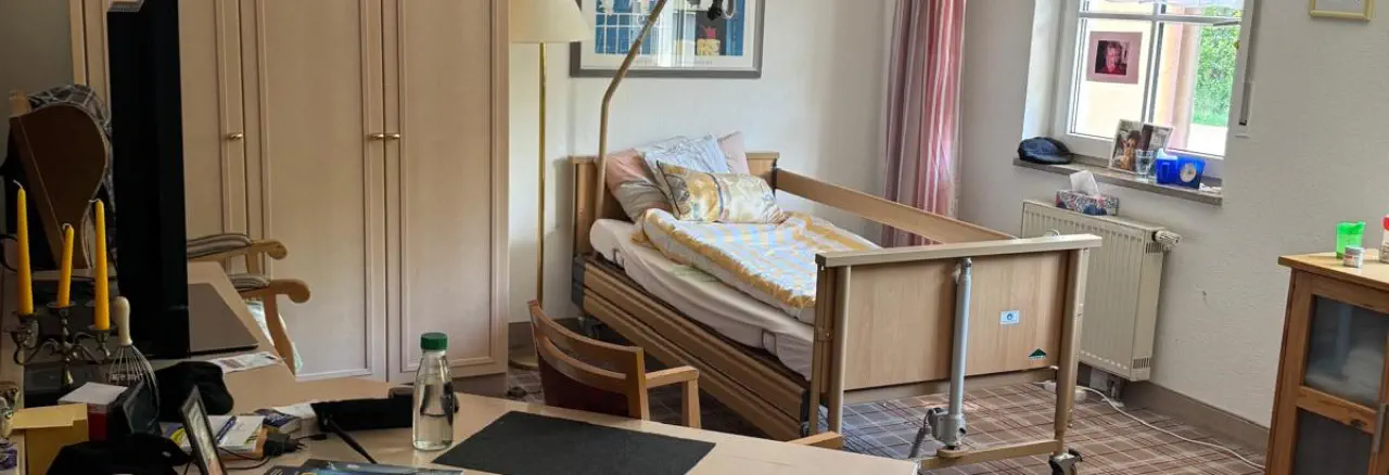 Geräumiges, persönlich möbliertes Bewohnerzimmer mit Pflegebett, Kleiderschrank und vertrauten Gegenständen am Fenster © Foto: Hambückers